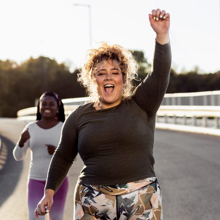 Two excited young plus size women jogging together.